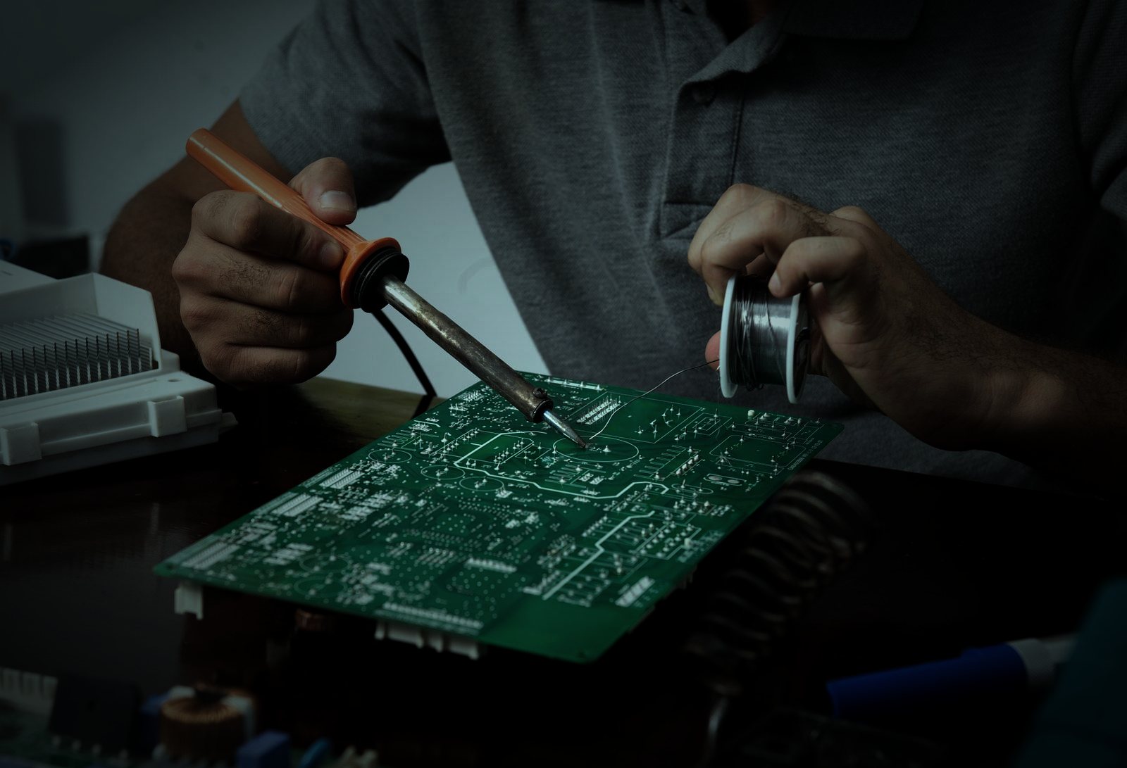 Lutowanie płytki elektronicznej w warsztacie, dłonie z lutownicą